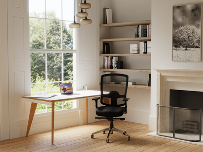 A modern home office scene featuring a black mesh office chair in front of built-in wooden shelves. Life style image